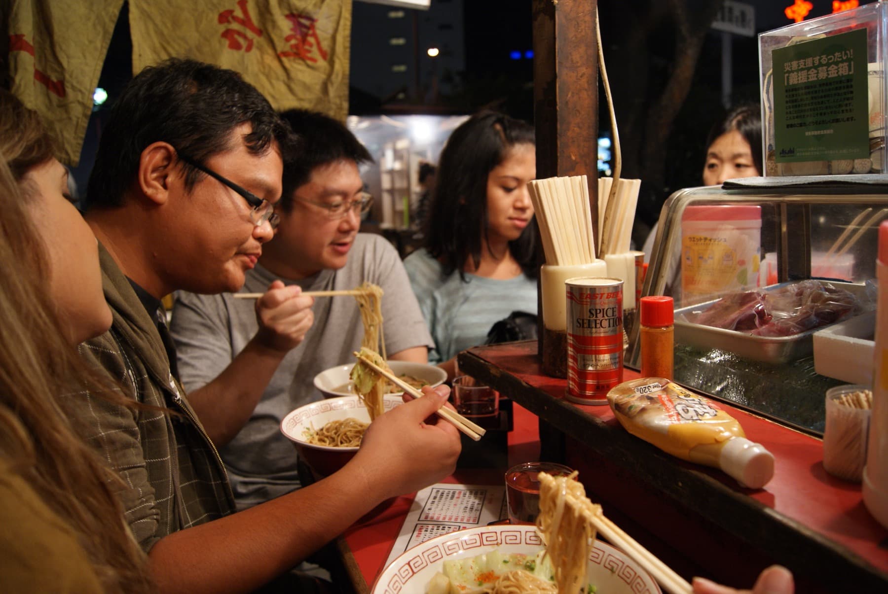 Gäster som äter ramen vid en yatai längs Naka-gawa i Fukuoka